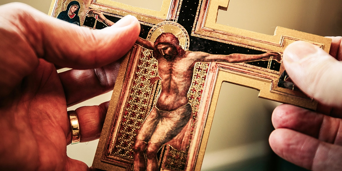person holding crucifix while praying