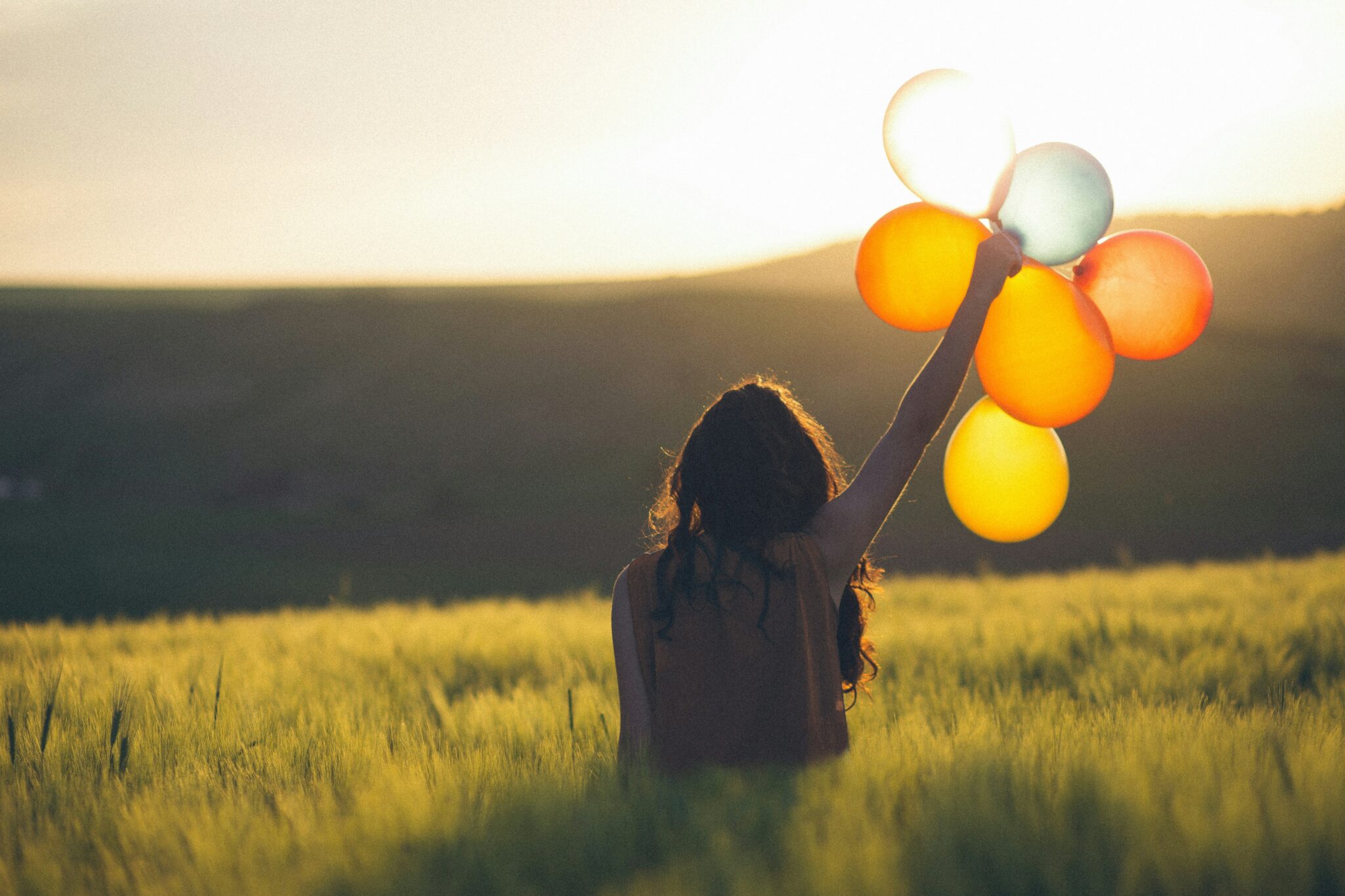 woman holding balloons | Photo by Catalin Pop on Unsplash
