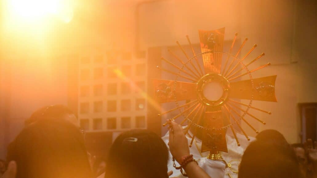 People holding the Eucharist | Photo by Erica Viana on Unsplash