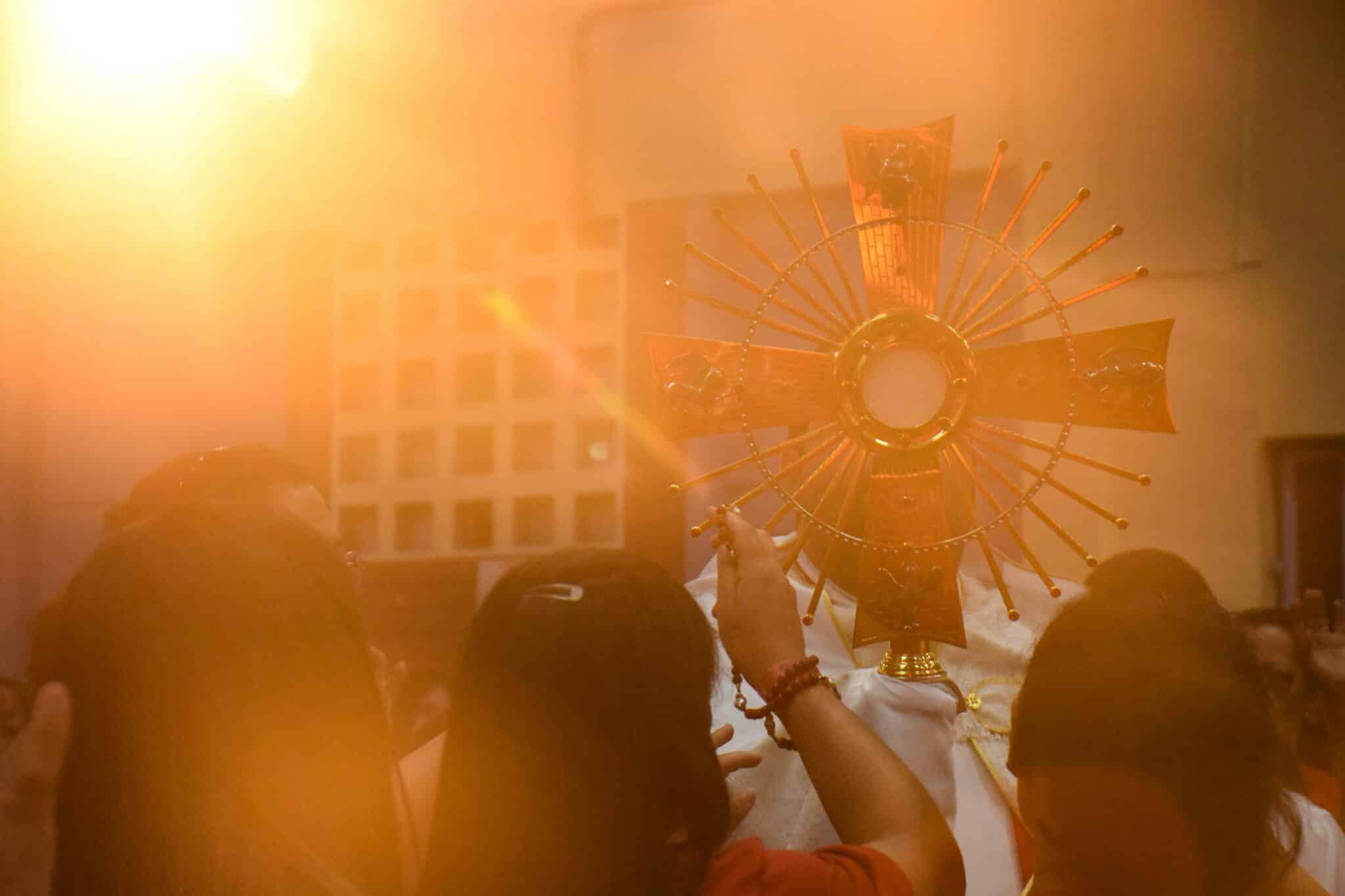 People holding the Eucharist | Photo by Erica Viana on Unsplash