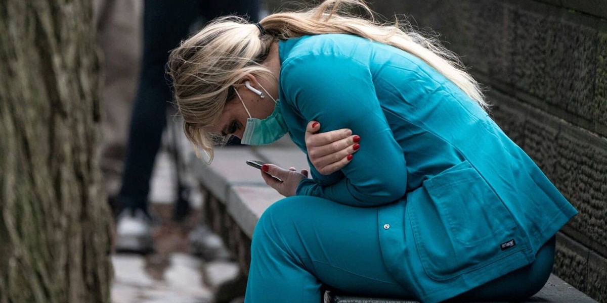 A nurse taking a break on a bench wearing a mask