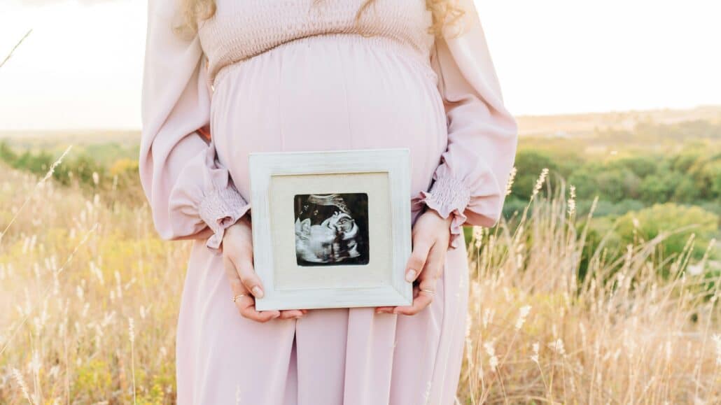Pregnant woman holding a picture | Photo by Bethany Beck on Unsplash