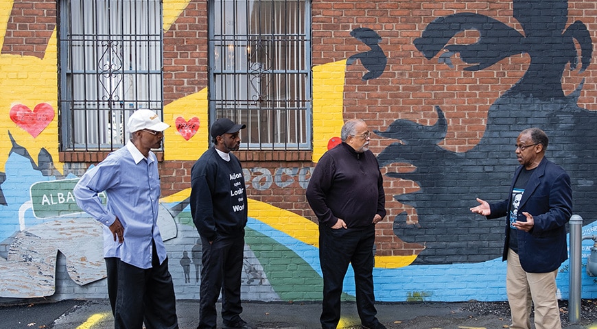 Deacon Miller talks with (from left) Burnell Bourgeois, Warren Hardy, and Rev. James Lane. The mural behind the men depicts Dr. Martin Luther King Jr.'s second principle of nonviolence, The Beloved Community