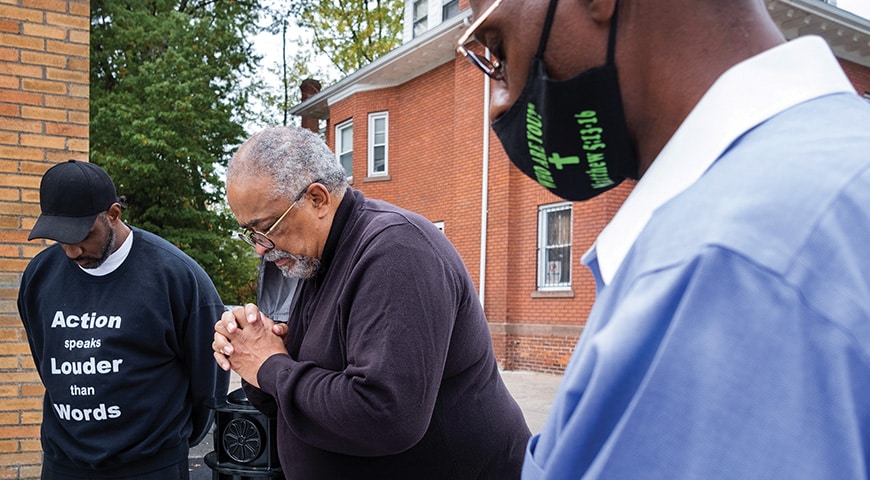 Deacon Miller prays alongside Warren Hardy, president of the Helping Young People Evolve (H.Y.P.E.), an at-risk youth and community support organization.