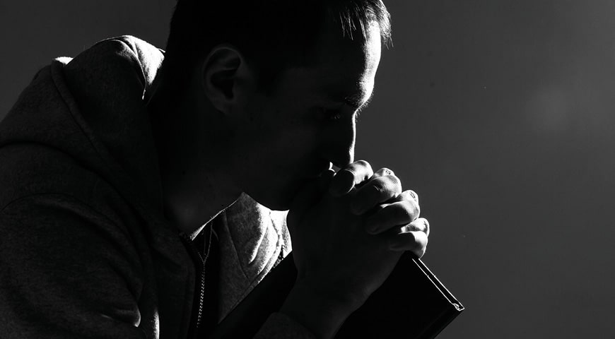 man holds a bible in prayer