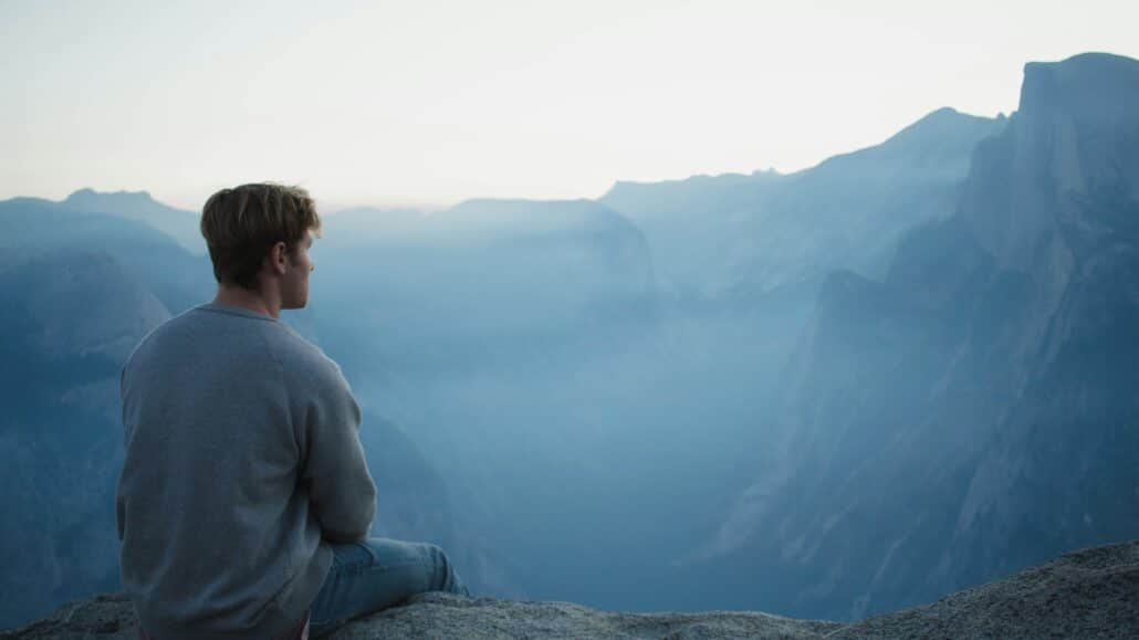 Man sitting on a cliff | Photo by Elijah Hiett on Unsplash