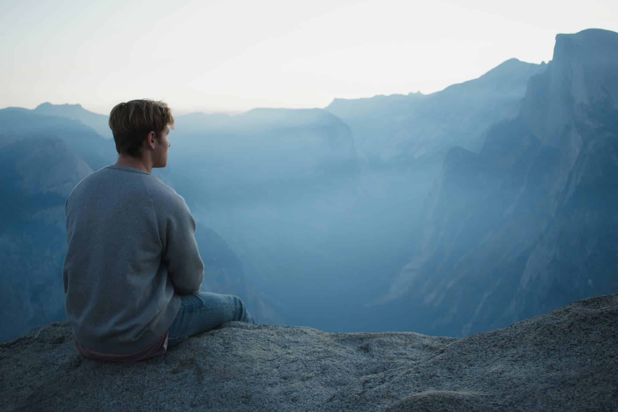 Man sitting on a cliff | Photo by Elijah Hiett on Unsplash