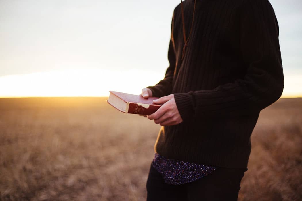 Person holding the Bible in a field