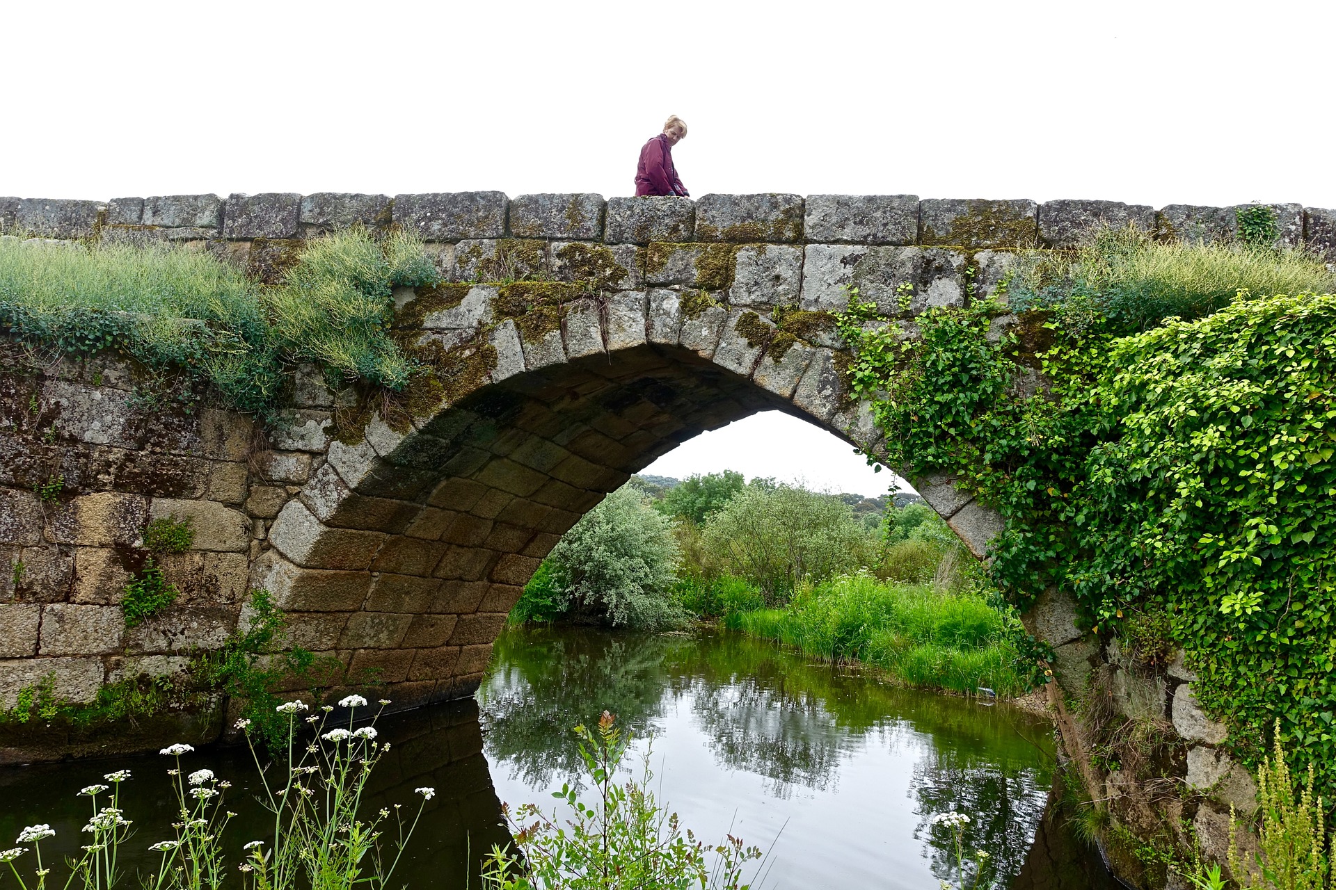 Person sitting on the side of a bridge