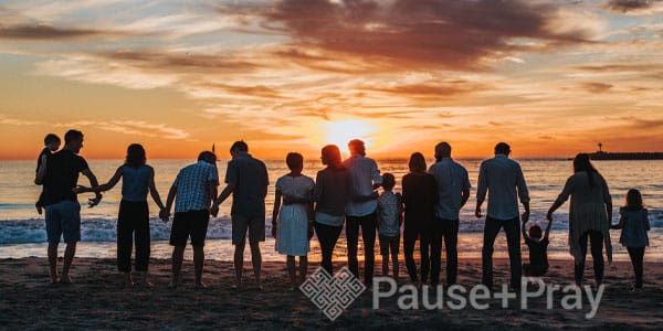 Family all holding hands during sunset looking at the ocean