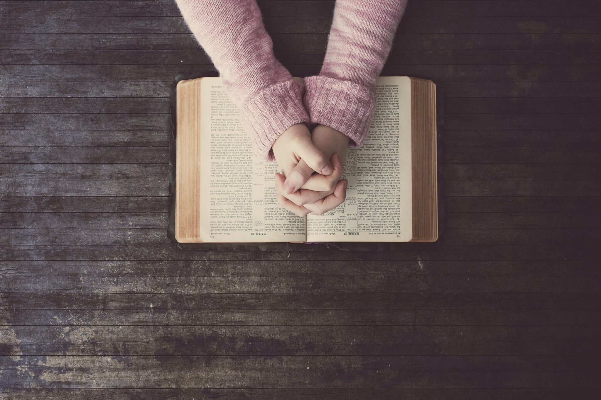 Hands folded together resting on a Bible