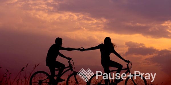 People holding hands during sunset while riding bikes