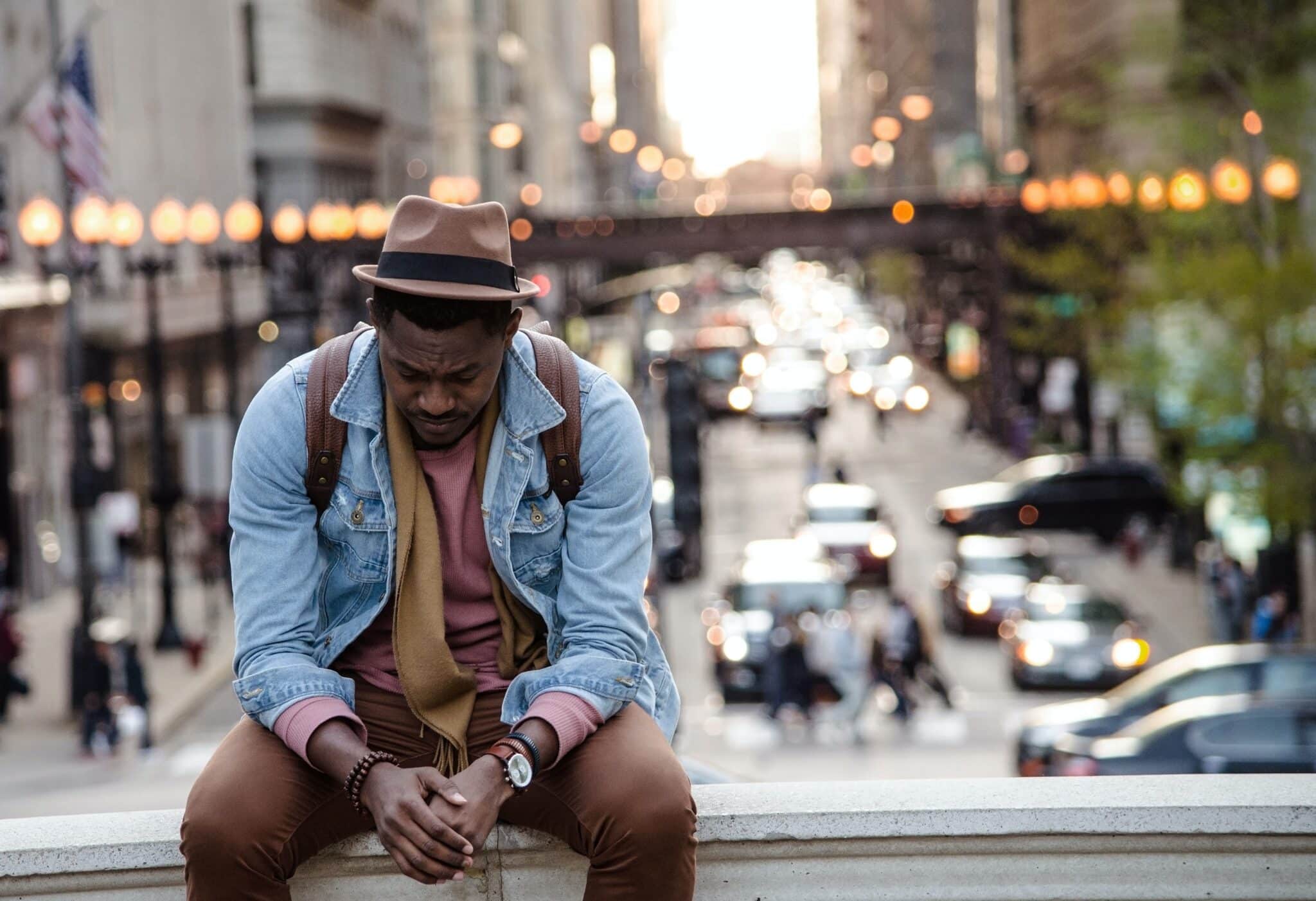 Man closes his eyes in prayer with street in the background