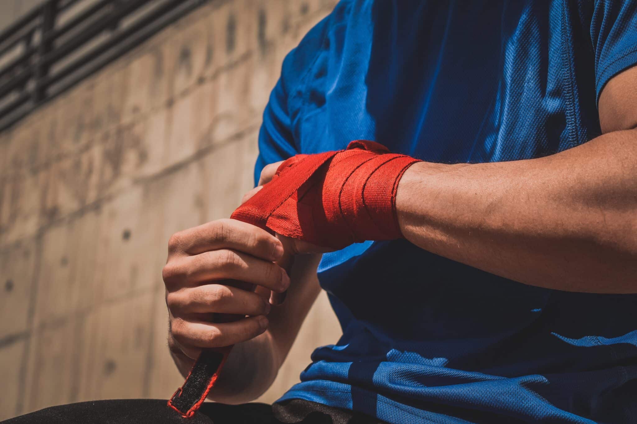 Person wrapping their hands with red boxing wrap