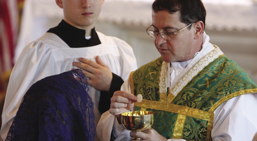 Priest gives Eucharist to a woman