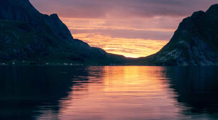 Sun setting over the water by the mountains