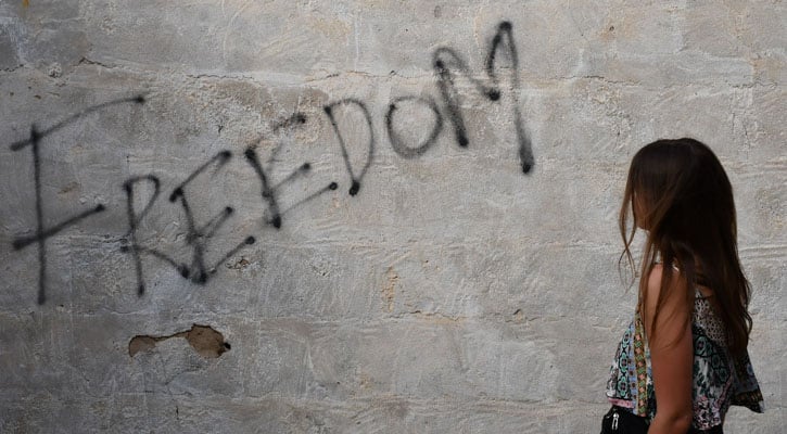 Woman looking at graffiti that says freedom