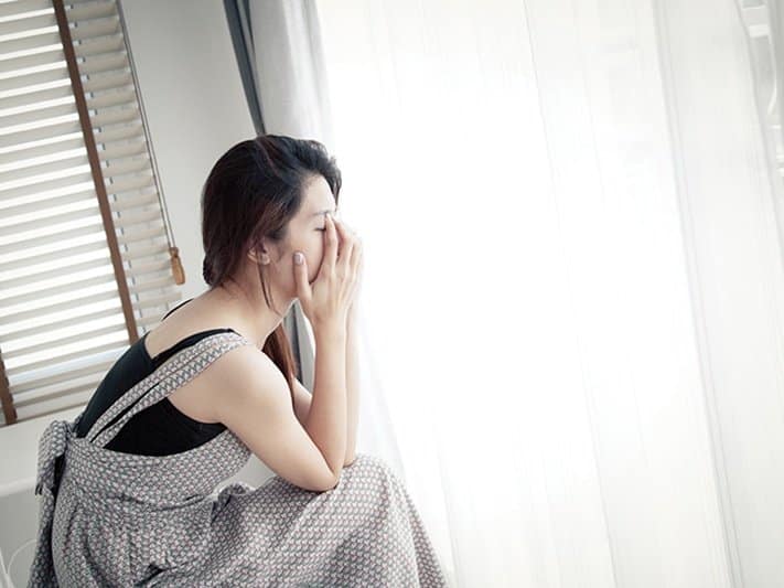 Person sitting down and holding her head in sadness