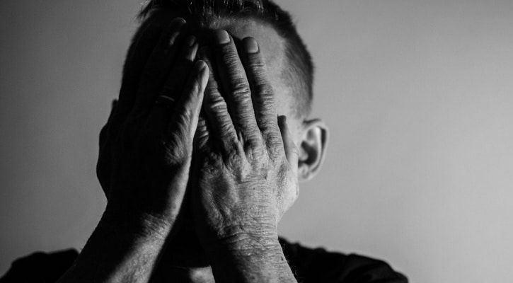 Anguished man with hands over his face