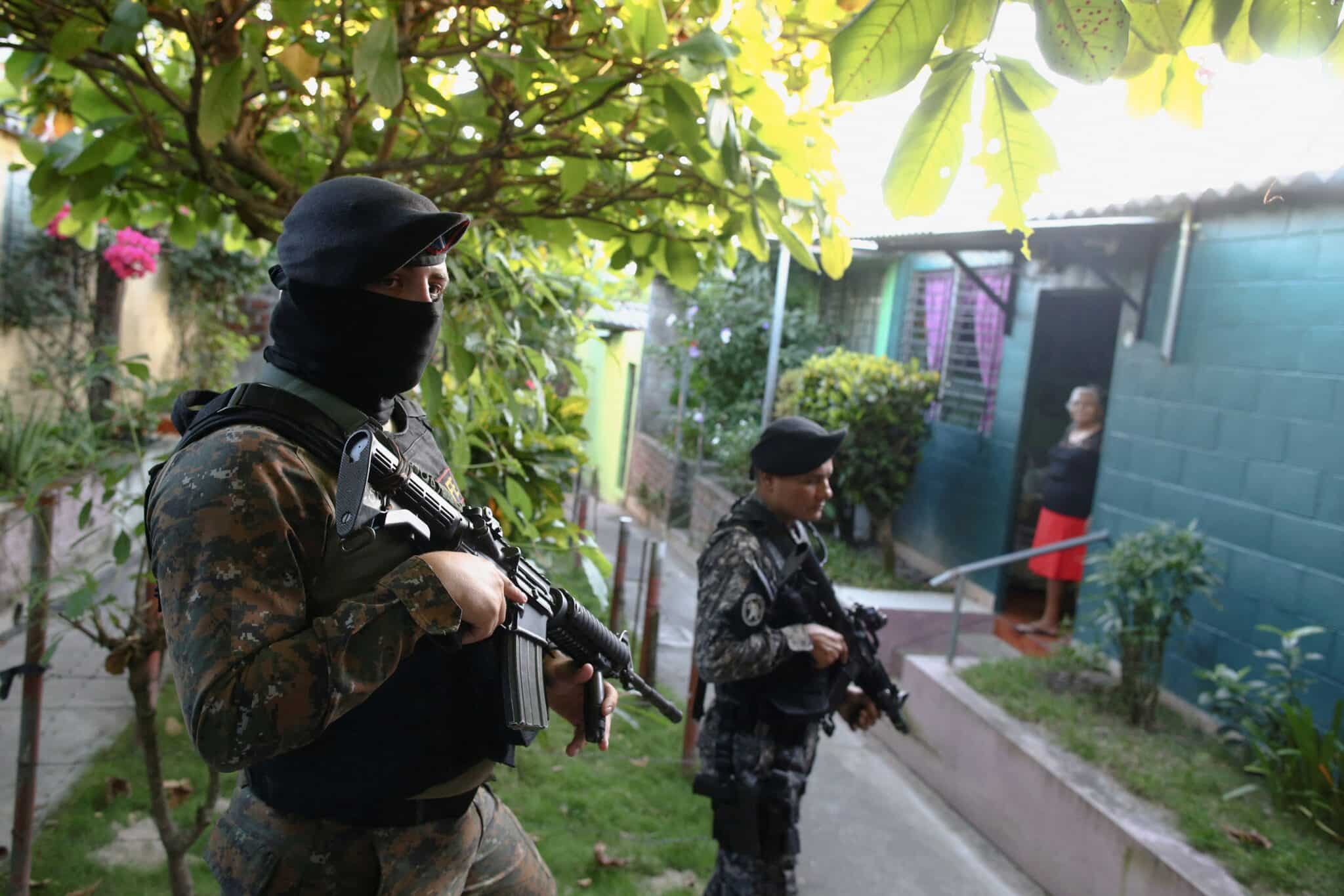 An elderly woman stands in her doorway as armed Salvadoran troops patrol a residential area in Soyapango Dec. 5, 2022. A massive crackdown on gangs in El Salvador has led to ongoing human rights abuses, says a new report. (CNS photo/Jose Cabezas, Reuters)