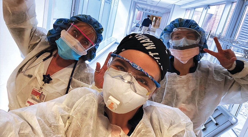 Three emergency room nurses pose for the camera in COVID masks