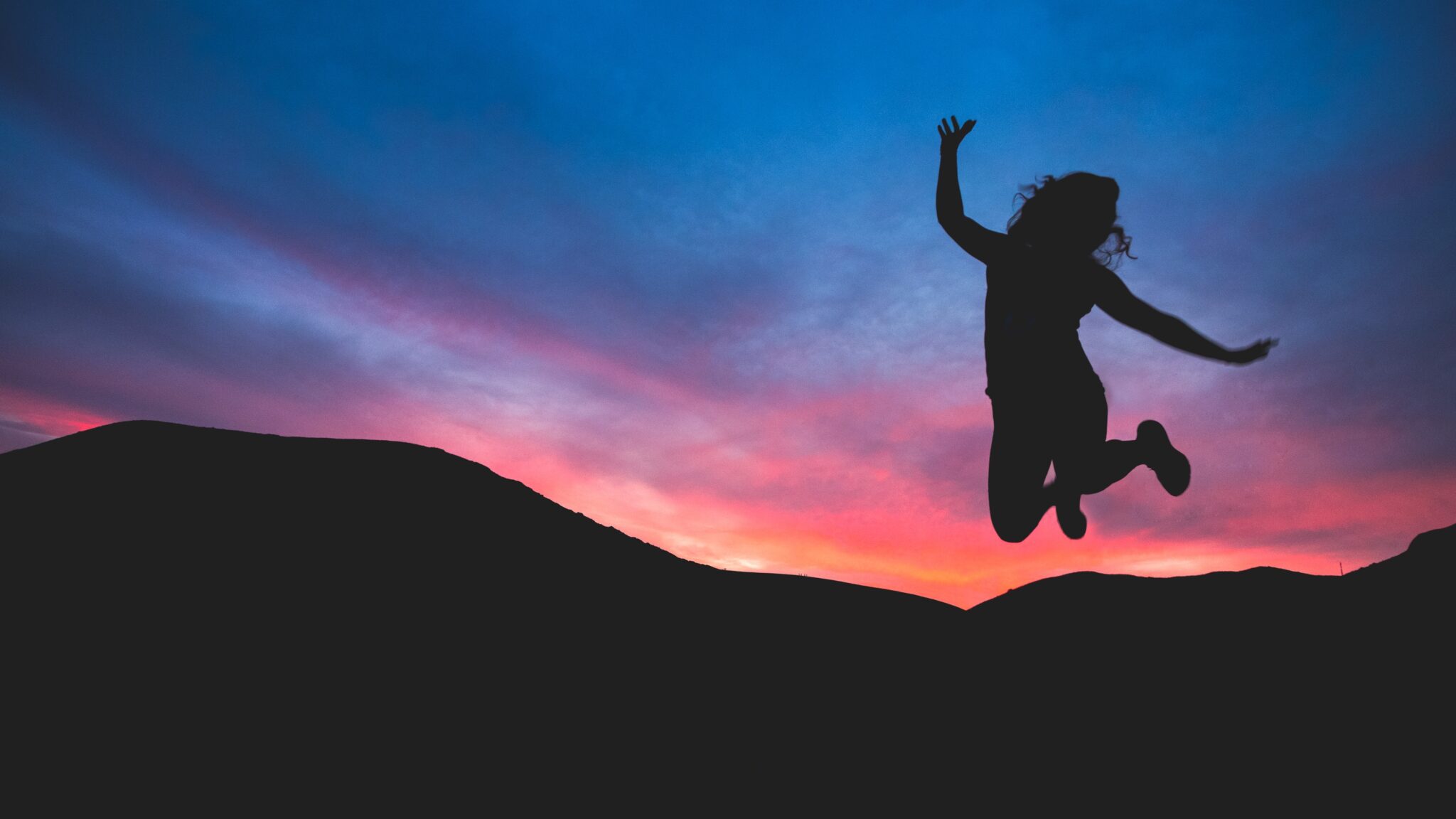Person jumping into the air during sunset