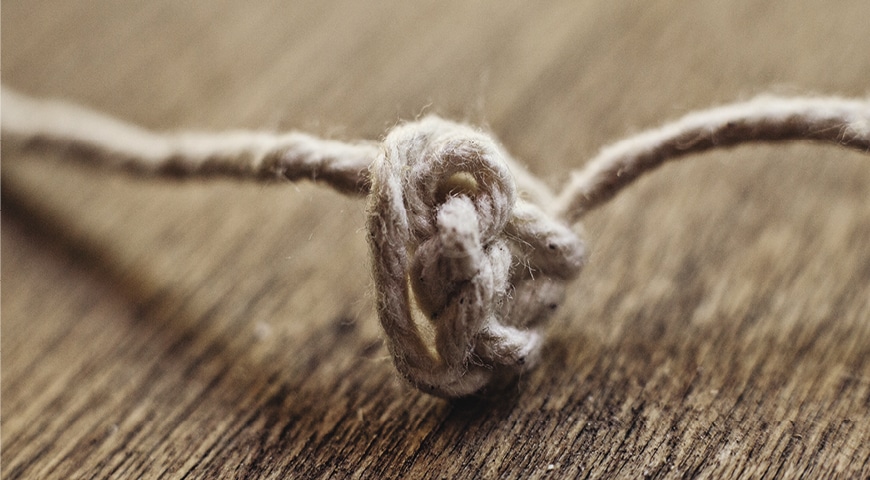 A knot made out of string sitting on a wooden table