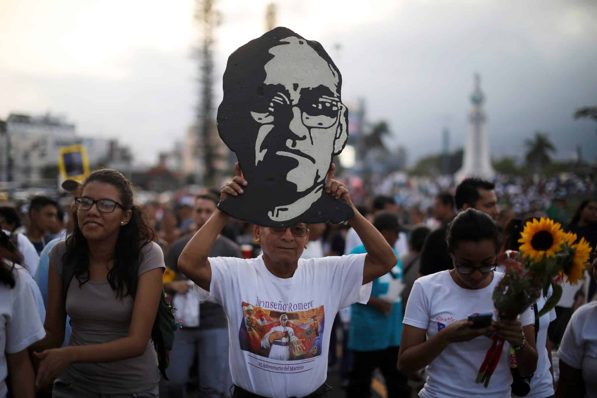 Man holding up a sign of Saint Oscar Romero