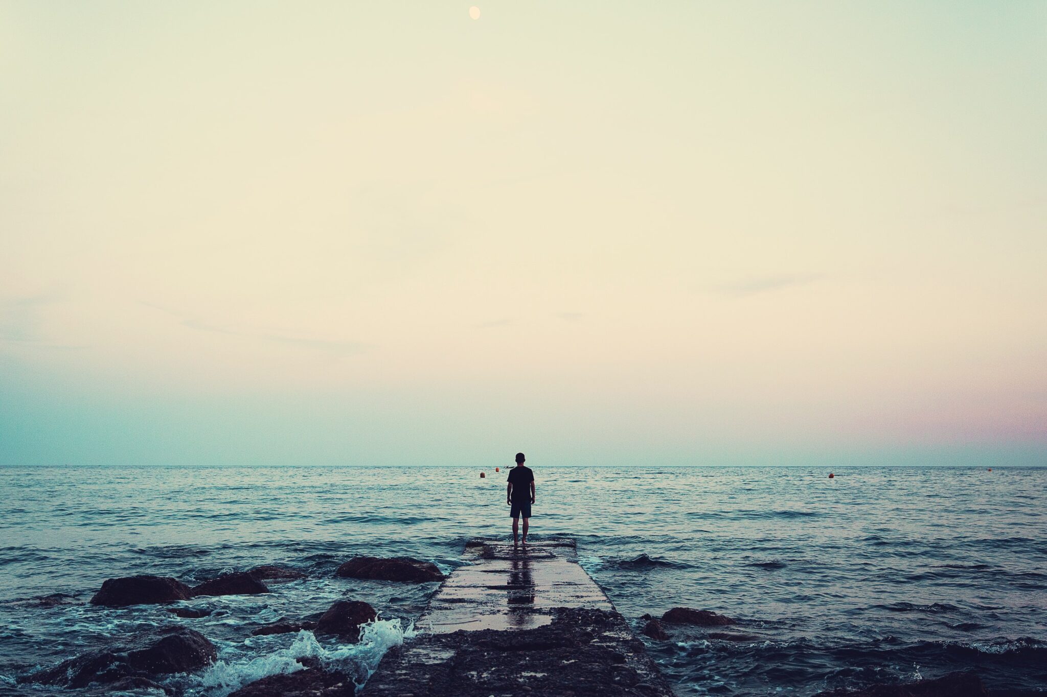 Man stands at the edge of the ocean | Photo by Joshua Earle on Unsplash