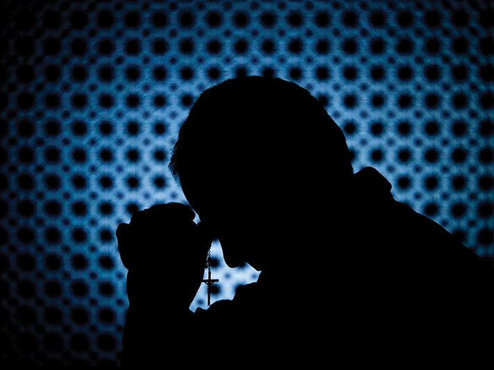 Person possibly praying with a cross in their hands