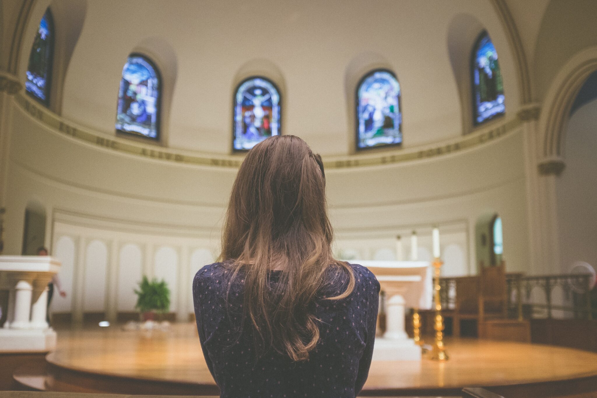 Woman praying in church | Photo by Kenny Eliason on Unsplash