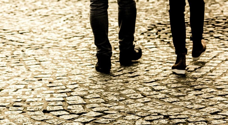 Two people walking on cobblestone street