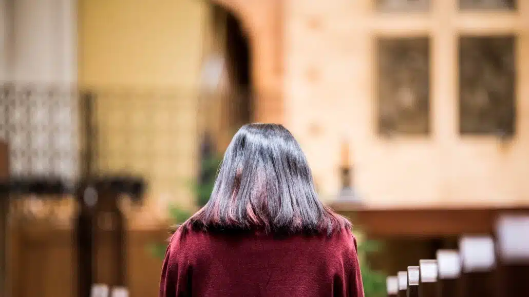 Woman praying in church | Photo by Gianna Bonello on Unsplash