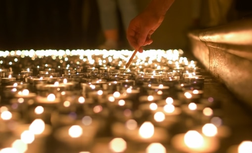 Person lighting a group of many candles
