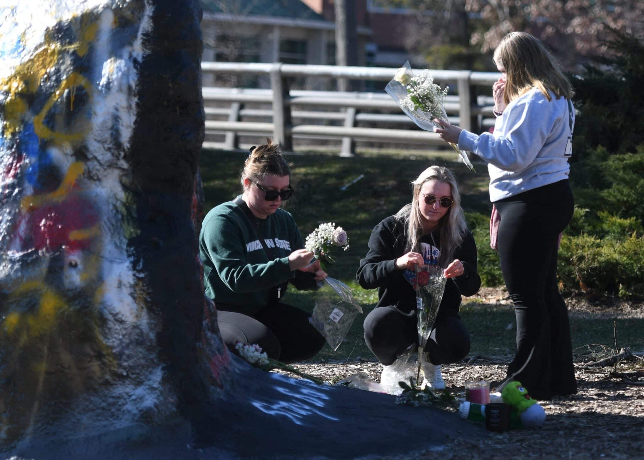 Michigan State University students place flowers at "The Rock" on campus Feb. 14, 2023, the day after after a mass shooting at the university in East Lansing. A gunman opened fire at at two university locations leaving three dead and five others critically injured. After an hourslong manhunt police found the shooter off campus dead of an apparent self-inflicted gunshot wound. (OSV News photo/Matthew Dae Smith, Lansing State Journal USA TODAY NETWORK via Reuters)