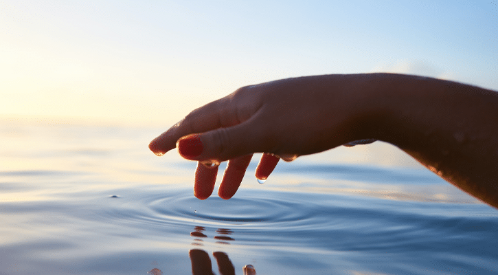 Hand reaching into water ripple