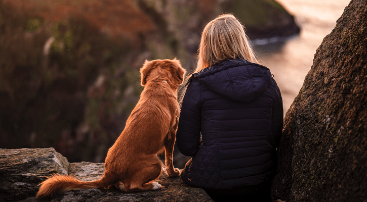 Woman and dog looking out at the sea