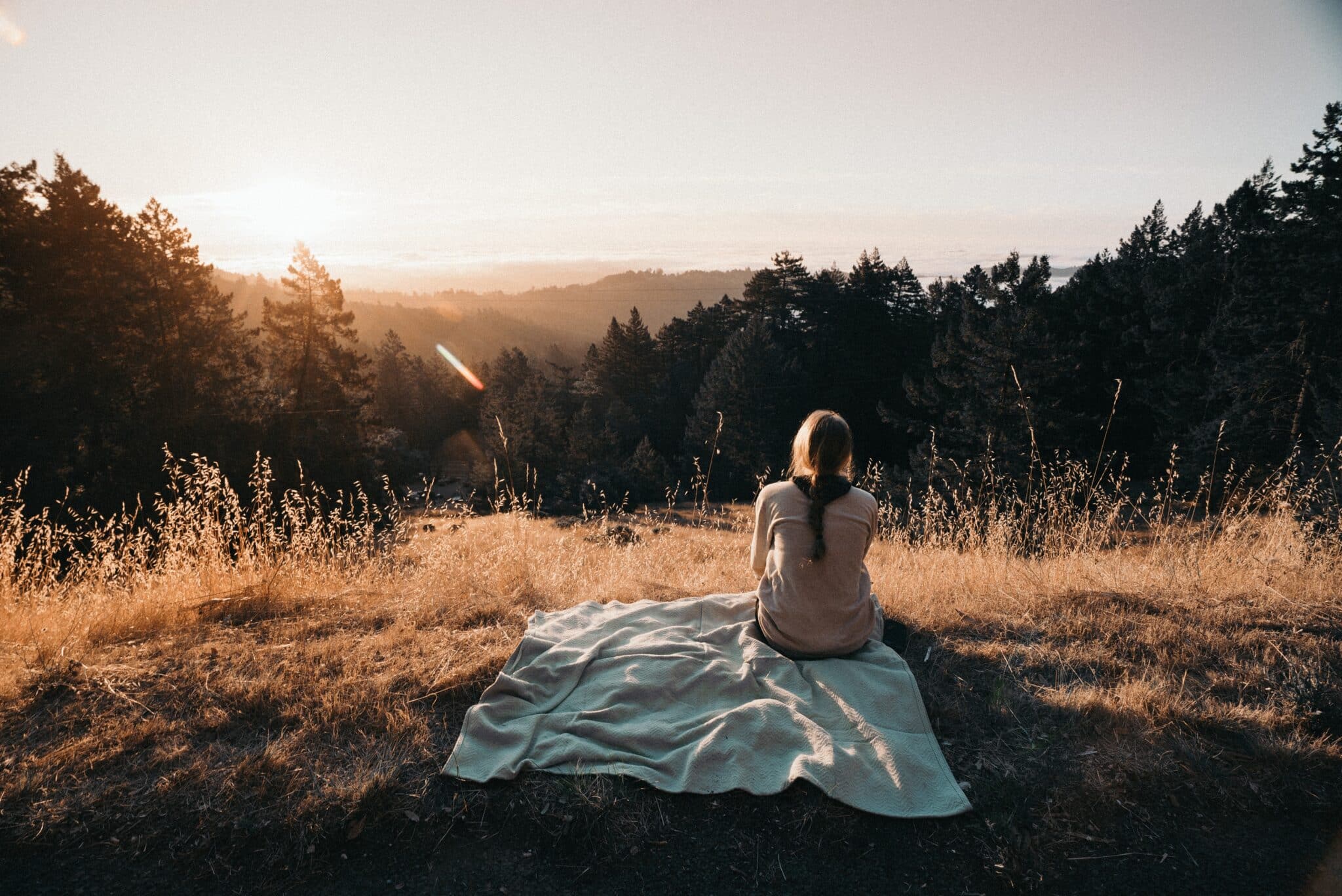 woman sits on a hill | Photo by Kevin Wolf on Unsplash