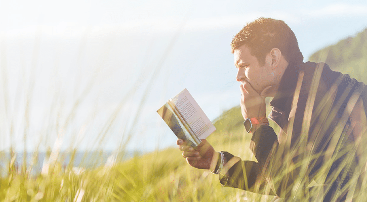 man reading a book outdoors
