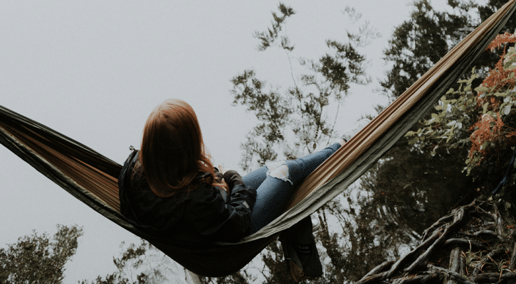 woman sitting in hammock by water