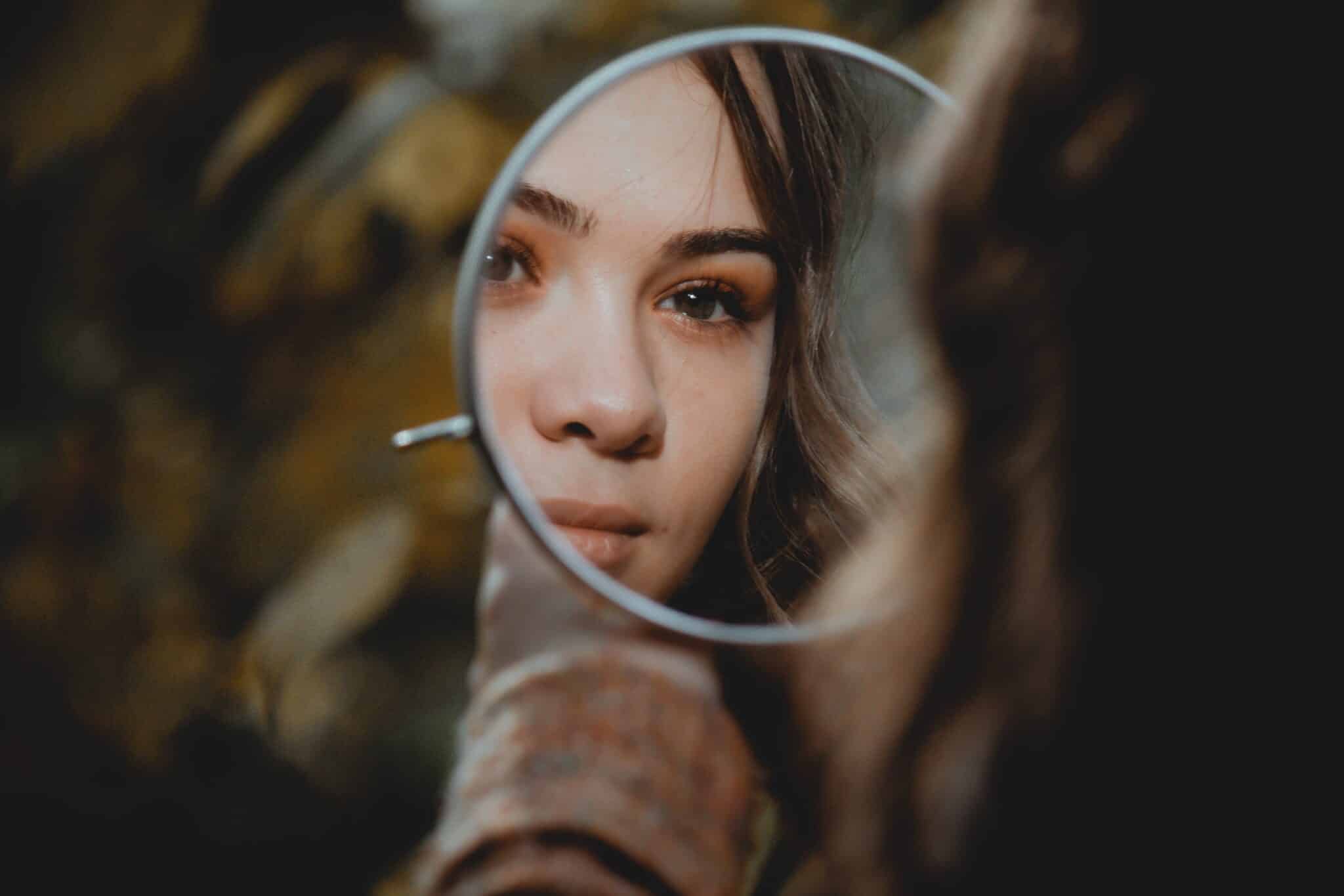 Woman looking in a mirror | Photo by Elisa Photography on Unsplash