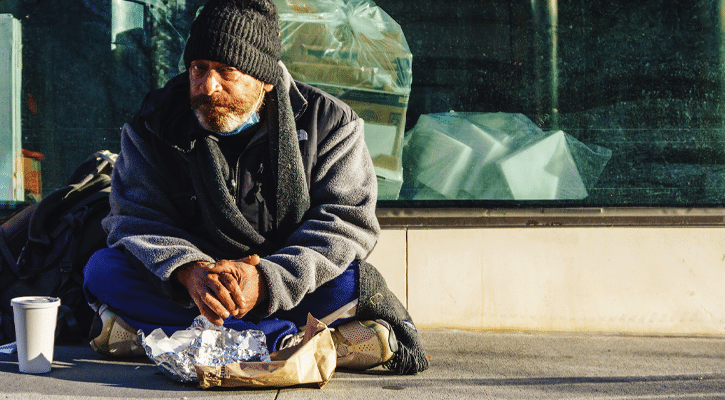 homeless man sitting on sidewalk