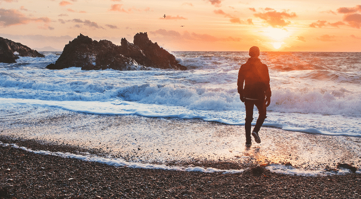 man walking into ocean waves