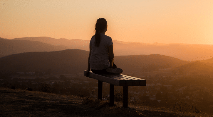 woman sitting on bench at sunset