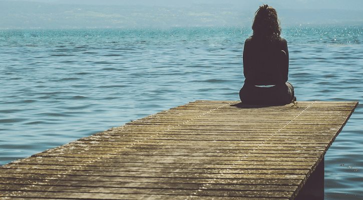 woman sitting at end of pier