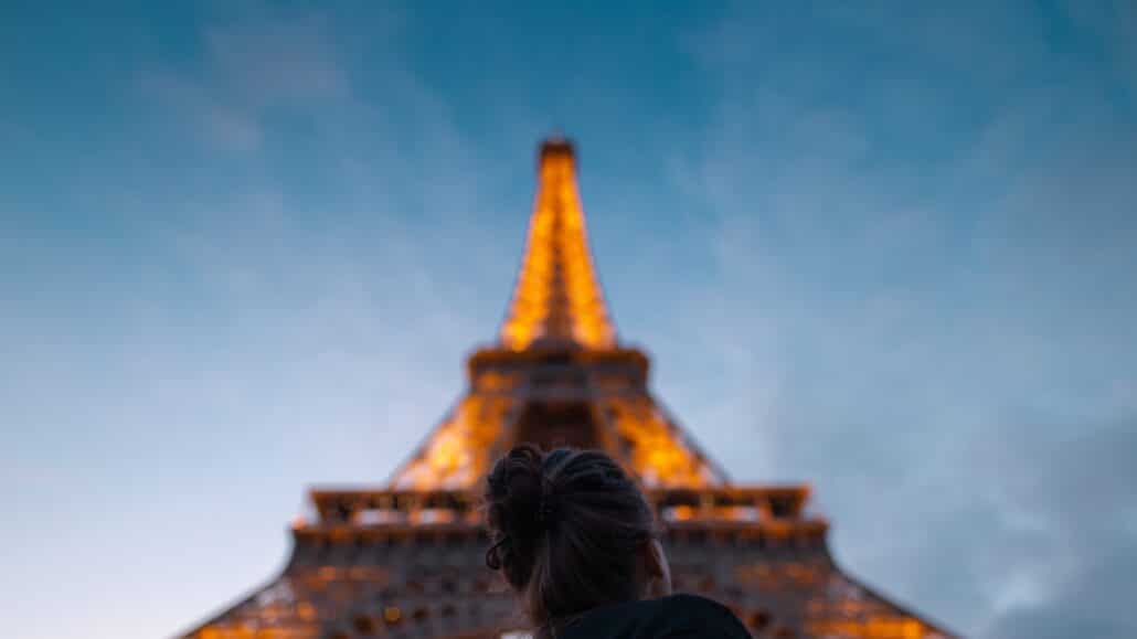 Woman stands under the Eiffel Tower | Photo by Christian Burri on Unsplash