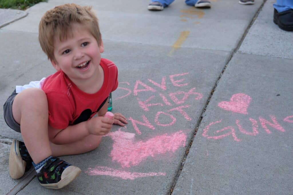 A 3-year-old boy plays with chalk as people gather for an event outside the Tennessee Capitol in Nashville April 18, 2023, to push the Legislature to address gun violence.  (OSV News photo/Katie Peterson, Tennessee Register)