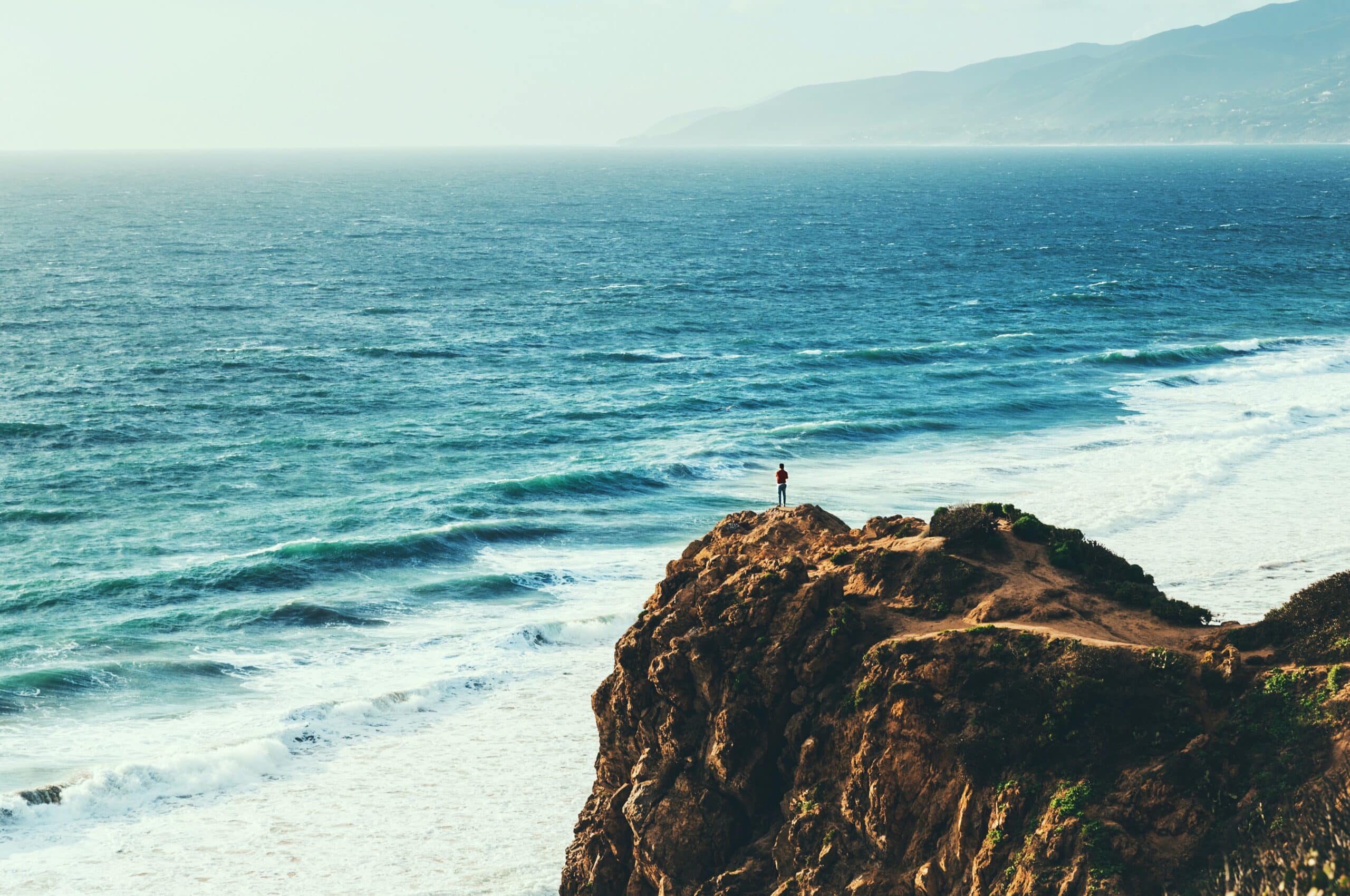 Man standing on a cliff | Photo by Austin Neill on Unsplash