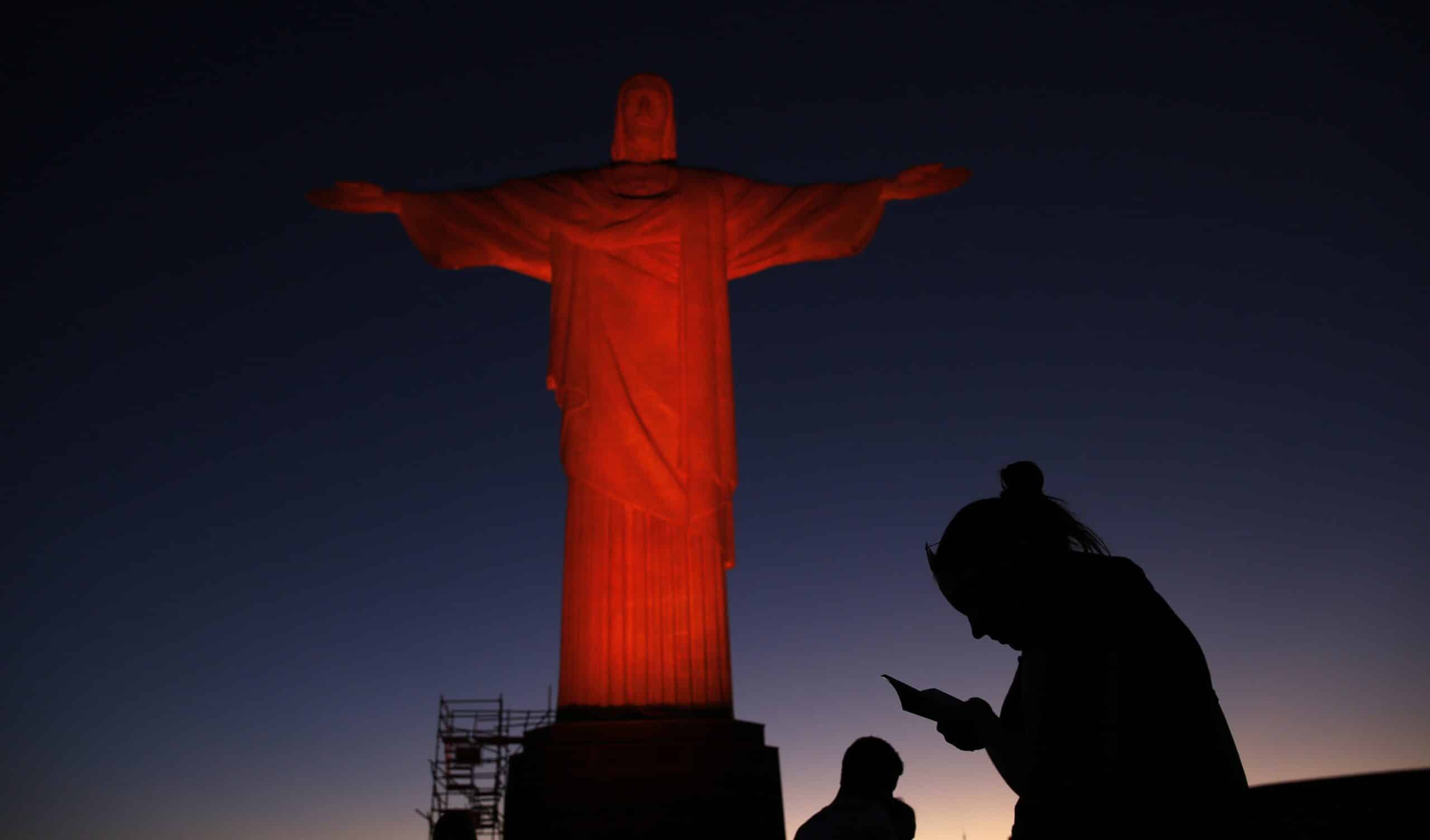 A person is pictured in a file photo praying in front of the statue of Christ the Redeemer as it is lit up in orange to commemorate the Day against Human Trafficking and Missing Persons, celebrated by the Archdiocese of Rio de Janeiro. (OSV News photo/Pilar Olivares, Reuters)