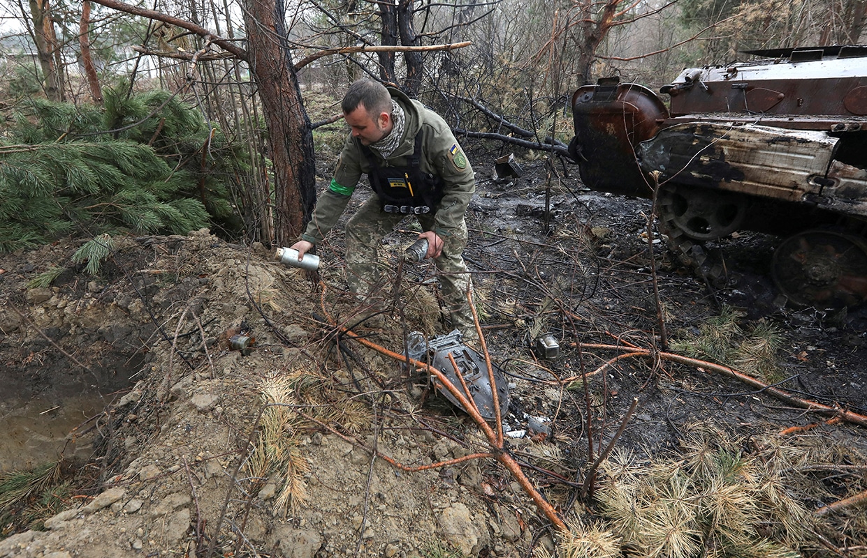 A Ukrainian soldier picks up unexploded parts of a cluster bomb left after Russia's invasion near the village of Motyzhyn, Ukraine, April 10, 2022. In a CNN interview July 9, 2023, U.S. President Joe Biden defended what he called a "very difficult decision" to provide cluster munitions to Ukraine amid Russia's invasion of that country, weapons the Vatican opposes. (OSV News photo/Mykola Tymchenko, Reuters)